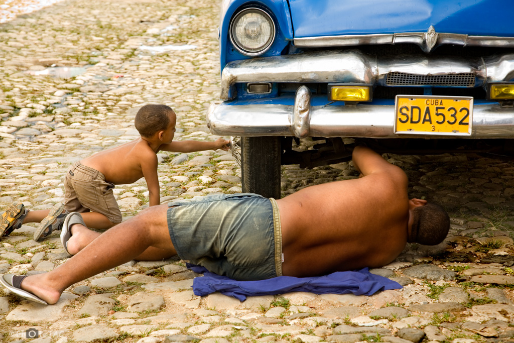 Cuba. Reparando un vehículo antiguo en las calles empedradas del casco antiguo de Trinidad (Sancti Spíritus).